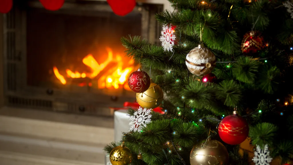 Warm inviting fireplace near decorated Christmas tree