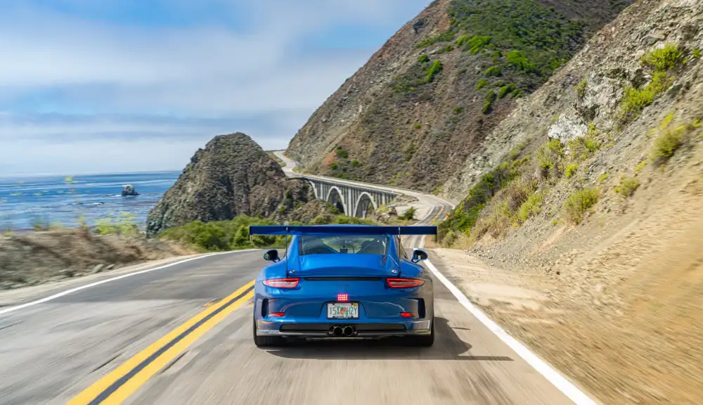Hero Image: Car driving on scenic costal road.